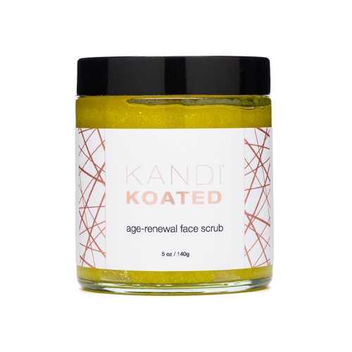 A jar of Kandi Koated Age-Renewal Face Scrub on a white background. The jar has a black lid and a white and rose gold label.