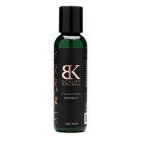 A narrow 2 ounce bottle of Coconut Dream body and beauty oil on a white background. The label is black and rose gold.