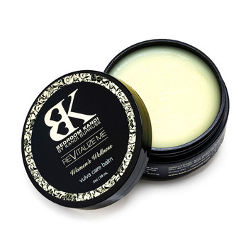 An open jar of the ReVitalize Me vulva care balm, the lid propped against the container, revealing the pale yellow surface of the balm inside.